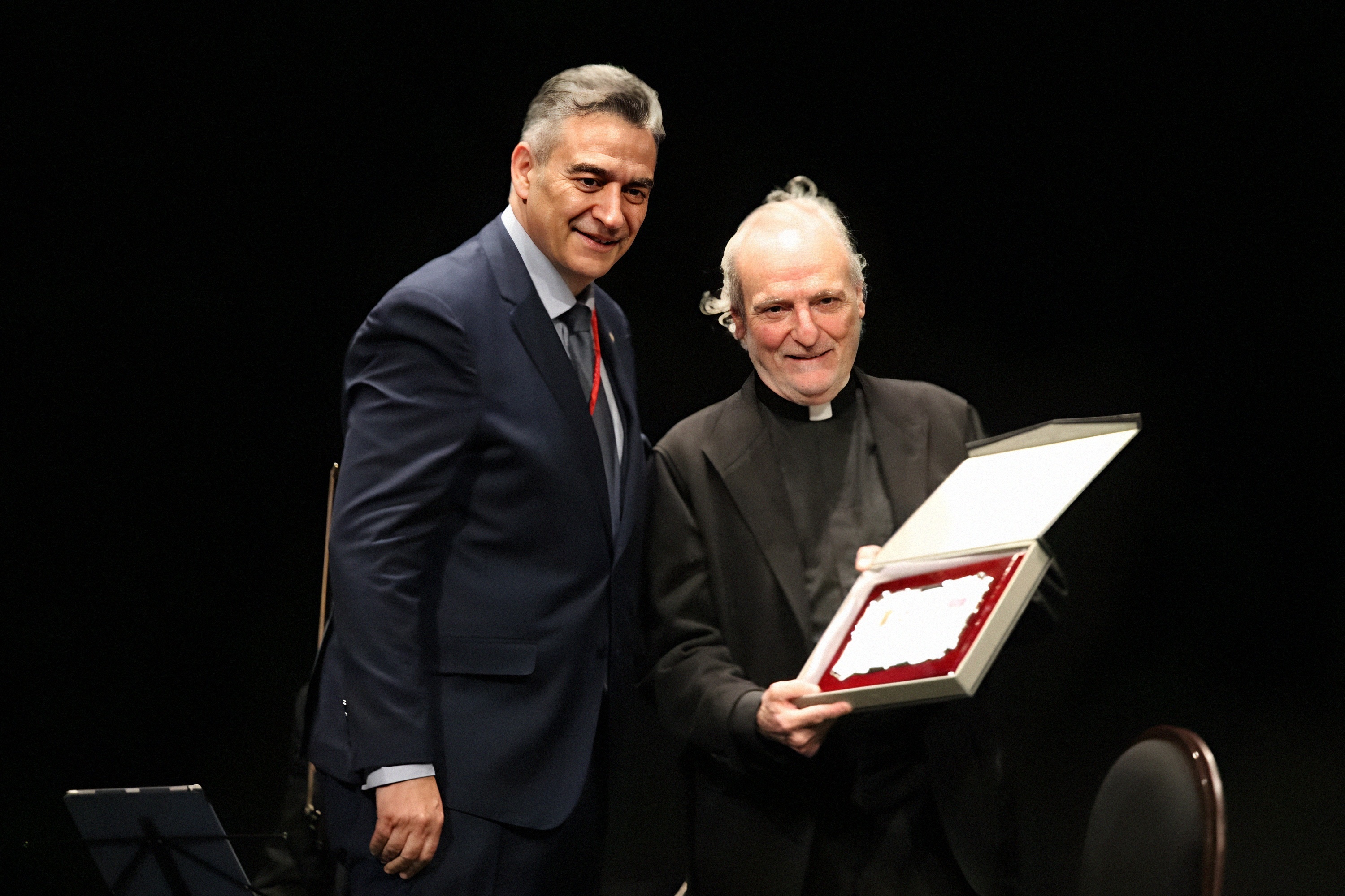 El sacerdote y periodista Juan Carlos Ramos, recibe un obsequio de manos del presidente de la Hermandad de Cofradías.