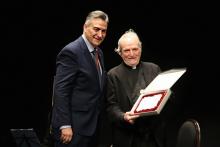 El sacerdote y periodista Juan Carlos Ramos, recibe un obsequio de manos del presidente de la Hermandad de Cofradías.